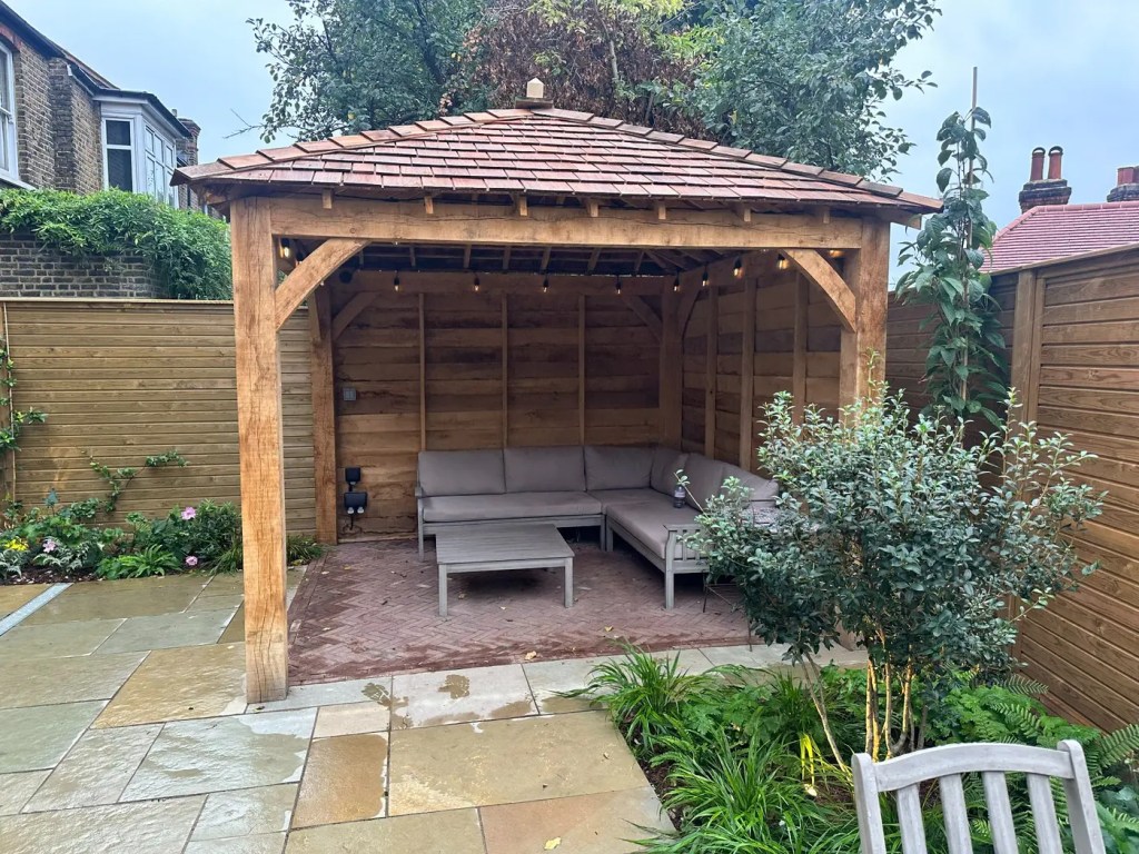 Bespoke oak pergola with a red cedar shingle roof in a completed Lewisham garden.