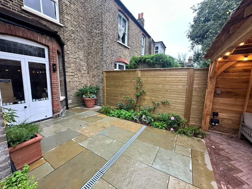 Jacksons Fencing panels installed beside a natural limestone patio in Lewisham.