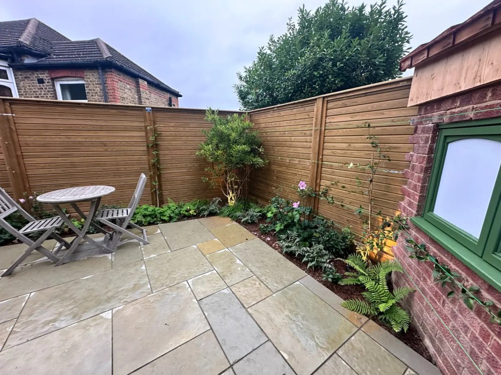 Year-round planting beside a natural limestone patio in a landscaped Lewisham garden.