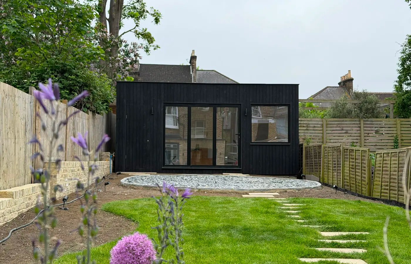 Bespoke black timber garden room built in a landscaped South London garden.
