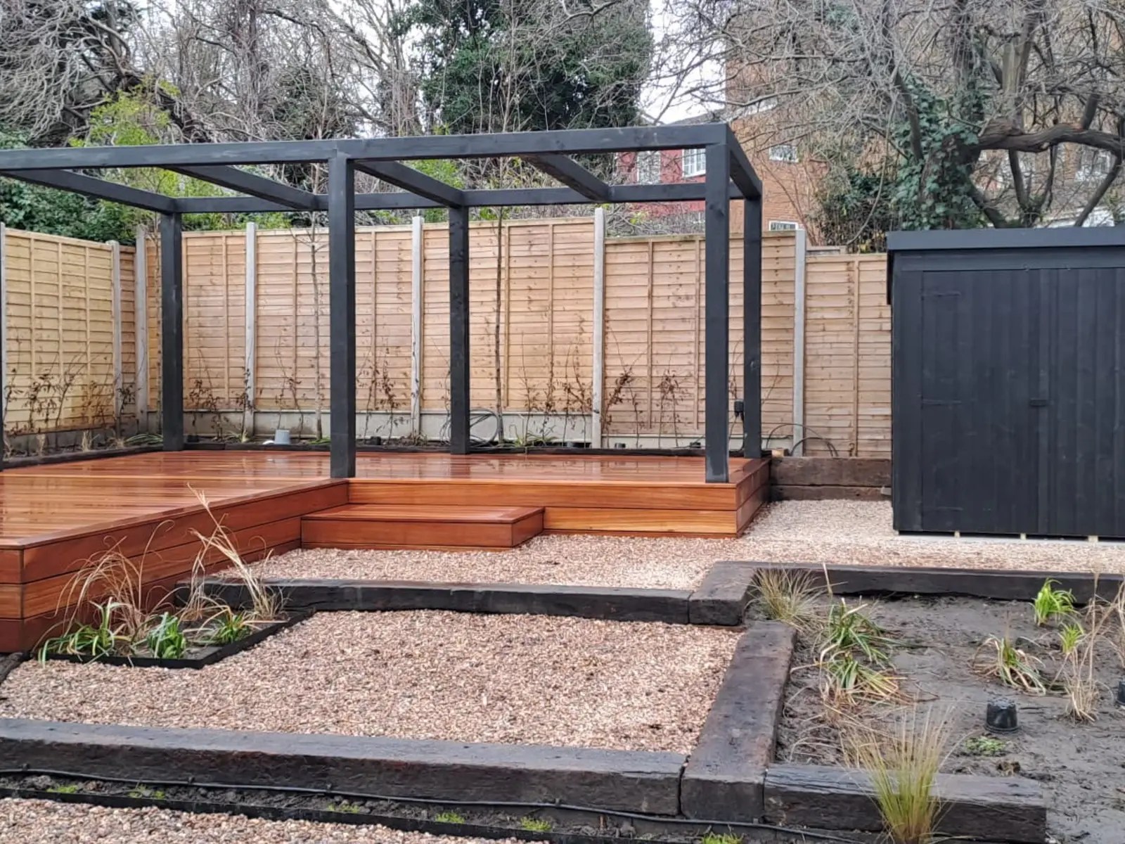 Timber decking with steps and a garden structure within a landscaped South London garden.